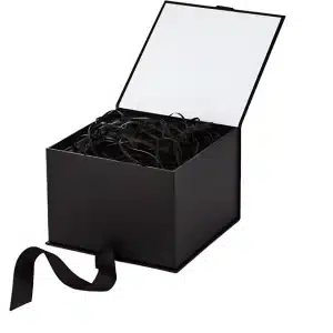 An open black box containing black paper filler, with a black ribbon hanging from it, and a note saying the paper filler can be crumpled for more volume.