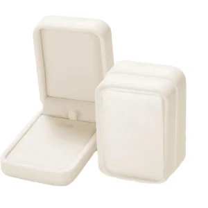 A pair of elegant drop style earrings with sparkling gemstones are nestled in a plush maroon velvet jewelry box.