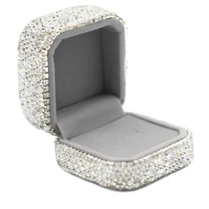 Відкрита скринька для коштовностей, інкрустована мерехтливими стразами, із плюшевою сірою внутрішньою підкладкою.