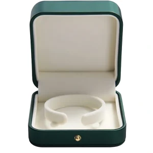 根据这张图，给我一句alt text An open dark green jewelry box with a white interior, containing a white velvet bracelet holder.