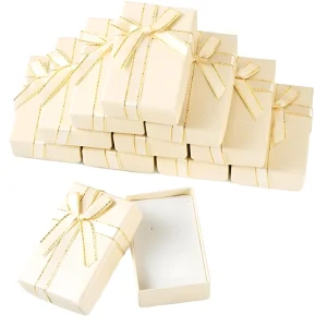 A stack of elegant beige gift boxes, each adorned with a golden ribbon tied into a bow, and one box shown open to reveal a white interior.