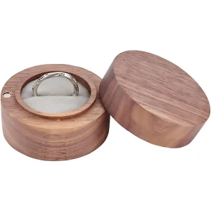 A round wooden jewelry box with a soft interior, holding a silver ring, its lid ajar.