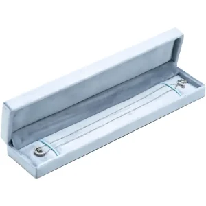A delicate silver necklace is placed inside a light-blue velvet-textured jewelry box. The middle and the end of the necklace are secured with light-blue straps.