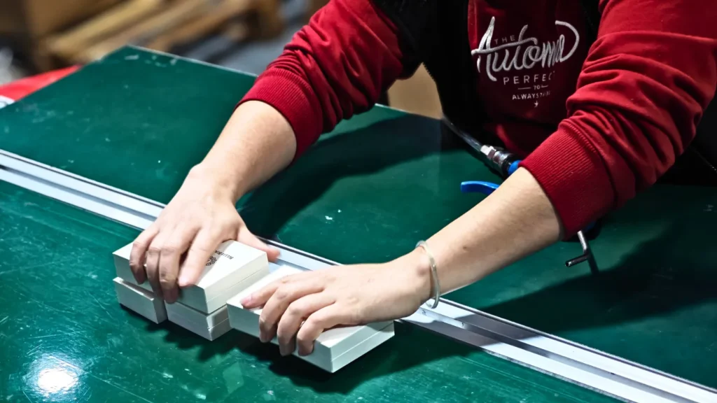 worker processing jewelry box components on green workbench