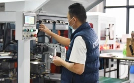 Jewelry box factory technician calibrating automated machine for box component shaping