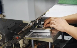 Artisan assembling jewelry box parts with precision machinery in a manufacturing workshop