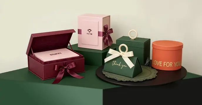 Curated luxury custom gift boxes in burgundy, pink, green, and orange with ribbon bows and branding, ideal for jewelry and premium gifting.