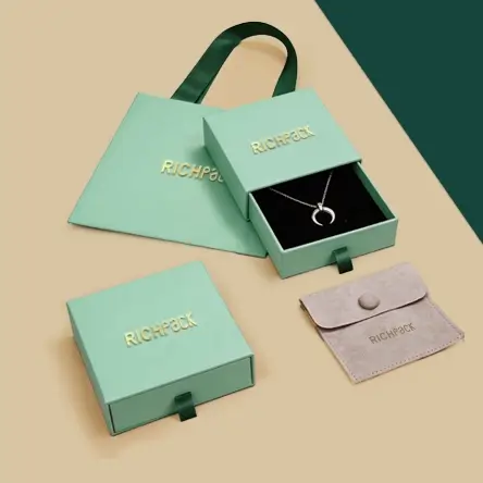 Mint green jewelry packaging set by Richpack: slide boxes, paper bag, and suede pouch with gold foil branding.