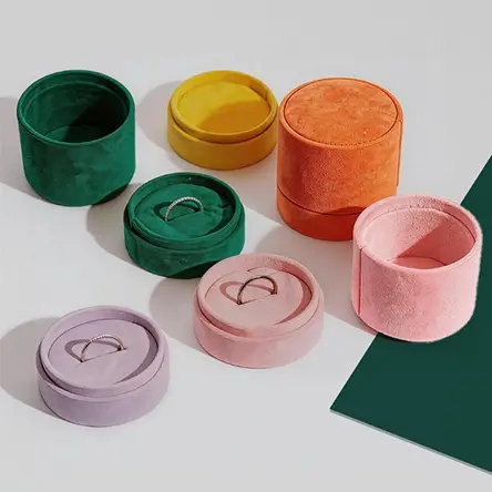 Colorful round velvet jewelry boxes in green, yellow, orange, pink, and lilac, with ring inserts for fine jewelry storage.
